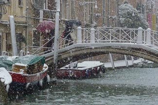 Umbrellas on a Venice bridge in the snow